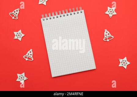 Hintergrund für Weihnachten Neujahr 2023 Weißes Notizbuch für Wünsche, Ziele, Rezepte, Pläne, Lösungen für den Beginn des neuen Jahres auf rotem Hintergrund zu Weihnachten Stockfoto