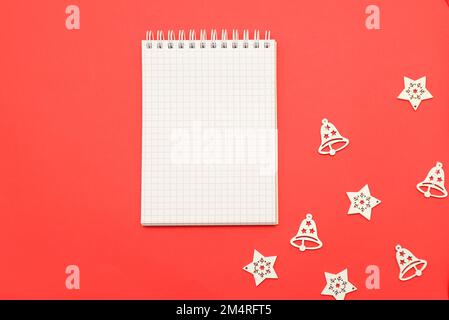 Hintergrund für Weihnachten Neujahr 2023 Weißes Notizbuch für Wünsche, Ziele, Rezepte, Pläne, Lösungen für den Beginn des neuen Jahres auf rotem Hintergrund zu Weihnachten Stockfoto