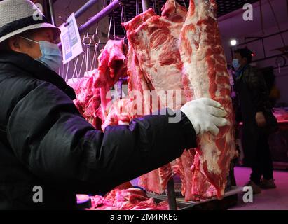 YICHANG, CHINA - 21. DEZEMBER 2022 - Menschen kaufen Schweinefleisch auf einem Markt in Yichang, Provinz Hubei, China, 21. Dezember 2022. Stockfoto