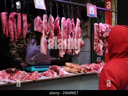 YICHANG, CHINA - 21. DEZEMBER 2022 - Menschen kaufen Schweinefleisch auf einem Markt in Yichang, Provinz Hubei, China, 21. Dezember 2022. Stockfoto