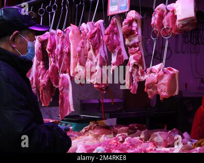 YICHANG, CHINA - 21. DEZEMBER 2022 - Menschen kaufen Schweinefleisch auf einem Markt in Yichang, Provinz Hubei, China, 21. Dezember 2022. Stockfoto