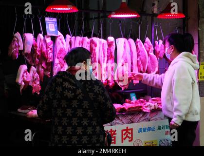 YICHANG, CHINA - 21. DEZEMBER 2022 - Menschen kaufen Schweinefleisch auf einem Markt in Yichang, Provinz Hubei, China, 21. Dezember 2022. Stockfoto