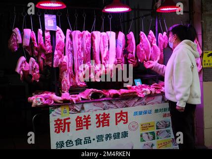 YICHANG, CHINA - 21. DEZEMBER 2022 - Menschen kaufen Schweinefleisch auf einem Markt in Yichang, Provinz Hubei, China, 21. Dezember 2022. Stockfoto