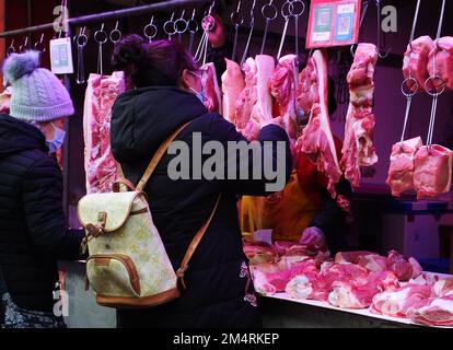 YICHANG, CHINA - 21. DEZEMBER 2022 - Menschen kaufen Schweinefleisch auf einem Markt in Yichang, Provinz Hubei, China, 21. Dezember 2022. Stockfoto