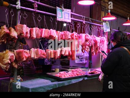 YICHANG, CHINA - 21. DEZEMBER 2022 - Menschen kaufen Schweinefleisch auf einem Markt in Yichang, Provinz Hubei, China, 21. Dezember 2022. Stockfoto