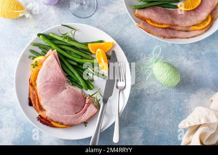 Osterschinken mit Spiralscheiben, serviert auf einem Teller mit grünen Bohnen Stockfoto