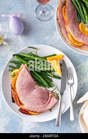 Osterschinken mit Spiralscheiben, serviert auf einem Teller mit grünen Bohnen Stockfoto