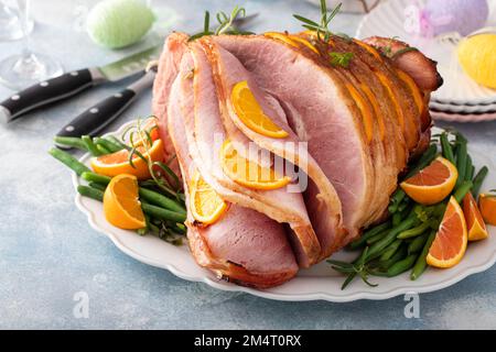 Osterschinken gefüllt mit Orangenscheiben und Kräutern, glasierter Schinken in Spiralscheiben Stockfoto