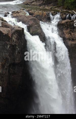 Eine vertikale Aufnahme eines großen Wasserfalls, der tagsüber die felsigen Klippen hinunterkommt Stockfoto