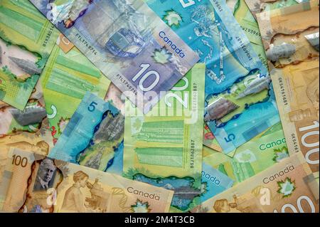 Calgary, Alberta - 21. Dezember 2022: Hintergrund mit verschiedenen kanadischen Banknoten, darunter 20-, 10-, 5- und 100-Dollar-Scheine. Stockfoto