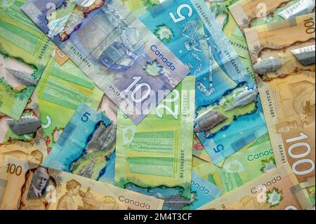 Calgary, Alberta - 21. Dezember 2022: Hintergrund mit verschiedenen kanadischen Banknoten, darunter 20-, 10-, 5- und 100-Dollar-Scheine. Stockfoto