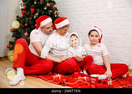 Fröhliche Familie, die neben dem Weihnachtsbaum lag. Porträt einer glücklichen Familie Stockfoto