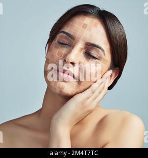 Es ist an der Zeit, diesen ungleichmäßigen Hautton auszugleichen. Eine junge Frau, die ihr Gesicht vor grauem Hintergrund berührt. Stockfoto