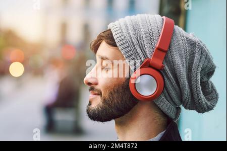 Keine Worte nötig, nur Musik. Ein junger Mann, der in der Stadt Musik hört. Stockfoto