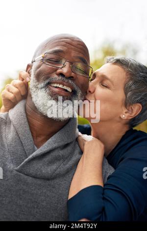 So verliebt wie am Tag ihres ersten Treffens. Ein liebevolles Seniorenpaar, das eine schöne Zeit im Park genießt. Stockfoto
