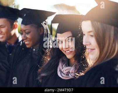 Gehen Sie selbstbewusst in die Richtung Ihrer Träume. Porträt einer Schülergruppe, die am Abschlusstag in einer Schlange steht. Stockfoto