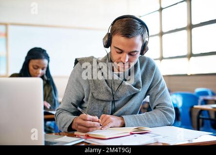 Er ist gewissenhaft und engagiert. Ein hübscher junger Student, der sich Notizen macht, während er im Unterricht sitzt. Stockfoto