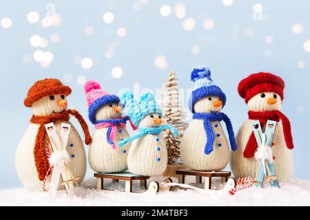 Gestrickte Schneemänner in farbenfrohen Mützen und Schals auf blauem Hintergrund. Das Konzept von Weihnachten, Neujahr und Wintermärchen. Flach verlegt Stockfoto
