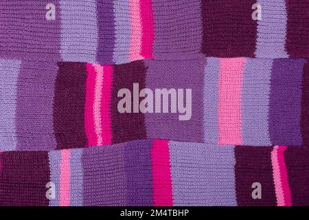 Gestrickter lilafarbener Hintergrund. Großer Strickstoff mit Muster. Wellenförmig faltet Material. Stockfoto