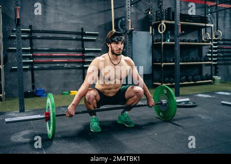 Porträt eines weißen, starken Mannes, der im Fitnessstudio Gewicht heben will Stockfoto