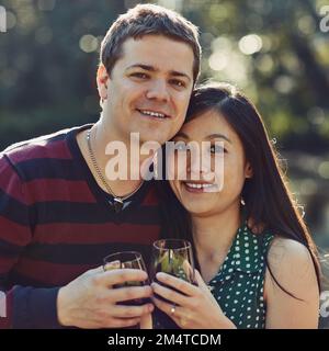 Wir fanden Liebe und hielten sie fest. Porträt eines glücklichen jungen Paares, das gemeinsam im Freien Wein genießt. Stockfoto