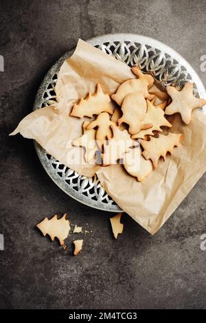 Weihnachtlich geformte Lebkekse auf Backpapier. Stockfoto