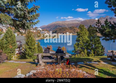 SANKT MORITZ, SCHWEIZ - 28,2022. OKTOBER: Ein Paar auf einem Banch in St. Moritz mit der Lake St. Moritz im Herbst, im Hintergrund der Berge Stockfoto