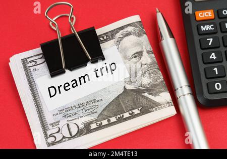 Business- und Economy-Konzept. Auf einer roten Oberfläche liegt ein Taschenrechner, ein Stift, Dollars. Dollars werden mit einer Klammer unter dem Papier mit der Inschrift befestigt Stockfoto
