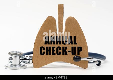 Medizinisches Konzept. Auf einer weißen Oberfläche befinden sich ein Stethoskop und eine Pappfigur einer Lunge mit der Aufschrift - JÄHRLICHE KONTROLLE Stockfoto