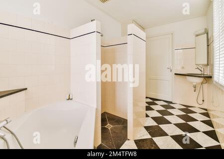 Ein Badezimmer mit schwarz-weiß karierten Fliesen auf dem Boden und eine Badewanne in der Ecke Stockfoto