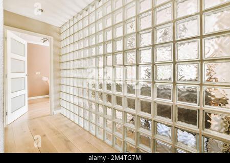 Ein leerer Raum mit vielen Glasblöcken an der Wand und Holzfußboden vor den Fensterscheiben Stockfoto