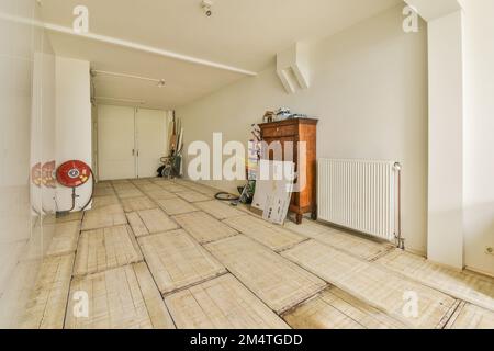 Ein unvollendeter Raum mit Holzfußboden und weißen Wänden im Raum wird als Arbeitsbereich für die Malerei genutzt Stockfoto