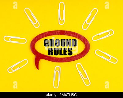 Business- und Economy-Konzept. Auf der gelben Oberfläche befinden sich Büroklammern und eine Platte, auf der die Beschriftung - GRUNDFLÄCHE DIE REGELN ENTHÄLT Stockfoto