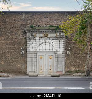 Weiße Holzbogentür, eingerahmt von weißen Marmordekorationen, in einer Steinmauer, Ciragan Street, Istanbul, Türkei Stockfoto