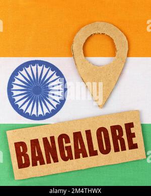 Das Konzept von Tourismus, Urlaub und Geolokation. Auf der indischen Flagge ein Geolokationssymbol und ein Schild mit der Inschrift Bangalore Stockfoto