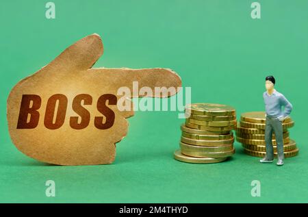 Business- und Economy-Konzept. Auf der grünen Oberfläche der Münze und der Figur eines Mannes sind sie durch ein Zeichen gekennzeichnet - eine Hand mit der Inschrift - bos Stockfoto