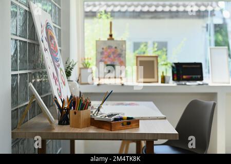 Interieur des Künstlerstudios mit Leinwand, Pinsel, Farbtupfer auf Holztisch. Malerraum mit Werkzeugen und Zubehör Stockfoto