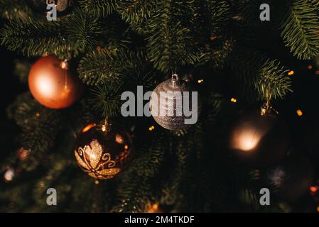 Schließen Sie die Kugeln am Weihnachtsbaum. Bokeh-Girlanden im Hintergrund. Neujahrskonzept. Stockfoto