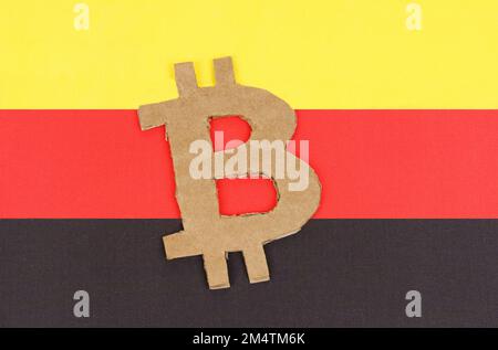 Kryptowährungskonzept. Auf dem Hintergrund der deutschen Flagge liegt das Symbol der Bitcoin. Stockfoto