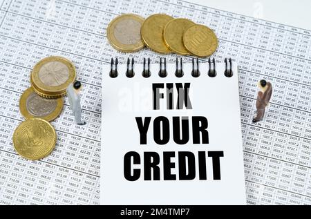 Geschäfts- und Finanzkonzept. In Finanzberichten finden Sie Figuren von Menschen, Münzen und einen Notizblock mit der Aufschrift "Fix Your Credit" Stockfoto
