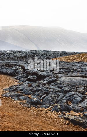 Vertikales Foto von os gekühlte Lava, die schwarze vulkanische Felsen an der Oberfläche bildet - Vulkan Geldingadalir Stockfoto