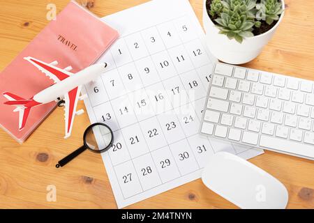 Kalender und Erinnerungen für Geschäftsreisen, Reisen und Urlaub. Gleiter auf dem Schreibtisch mit Flugzeug und Lupe, Stift und Tastatur. Markierung wichtig Stockfoto