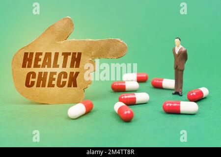 Medizin und Gesundheitskonzept. Auf grünem Hintergrund sind Pillen in Kapseln, eine Miniaturfigur eines Mannes und eine Handfigur mit der Inschrift - ER Stockfoto