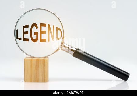 Wirtschaftskonzept. Auf einer weißen Oberfläche befinden sich ein Würfel und eine Lupe im Inneren, die die Beschriftung - Legende darstellt Stockfoto