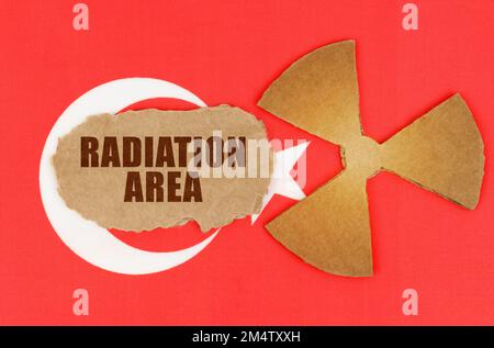 Industrie- und Strahlenbegriff. Auf der Flagge der Türkei das Symbol der Radioaktivität und zerrissener Karton mit der Aufschrift - Strahlenbereich Stockfoto