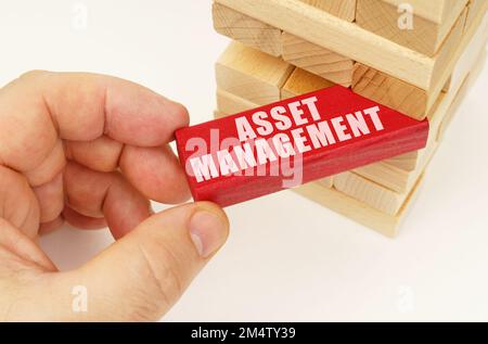 Geschäfts- und Technologiekonzept. Vom Turm mit Holzplanken nehmen sie eine rote Tafel mit der Inschrift "Asset Management" Stockfoto