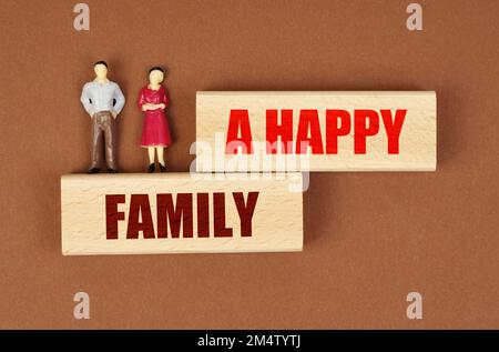 Menschen-Konzept. Auf Holzblöcken mit der Inschrift - Eine glückliche Familie - gibt es Miniaturfiguren von Menschen. Stockfoto