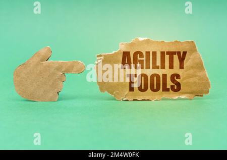 Geschäftskonzept. Auf einer grünen Oberfläche zeigt eine Kartonhand auf ein Schild mit der Aufschrift „Agility Tools“ Stockfoto