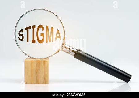 Wirtschaftskonzept. Auf einer weißen Oberfläche befinden sich ein Würfel und eine Lupe im Inneren, die die Inschrift - STIGMA - darstellt Stockfoto