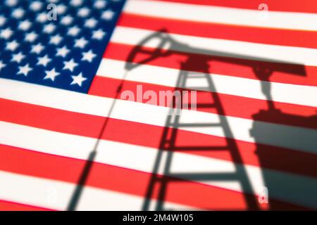 Die Ölindustrie der USA. Bohrinseln im Hintergrund der Flagge der Vereinigten Staaten von Amerika. Bergbau und Ölexport. Handel auf dem globalen Kraftstoffmarkt. Kraftstoff i Stockfoto